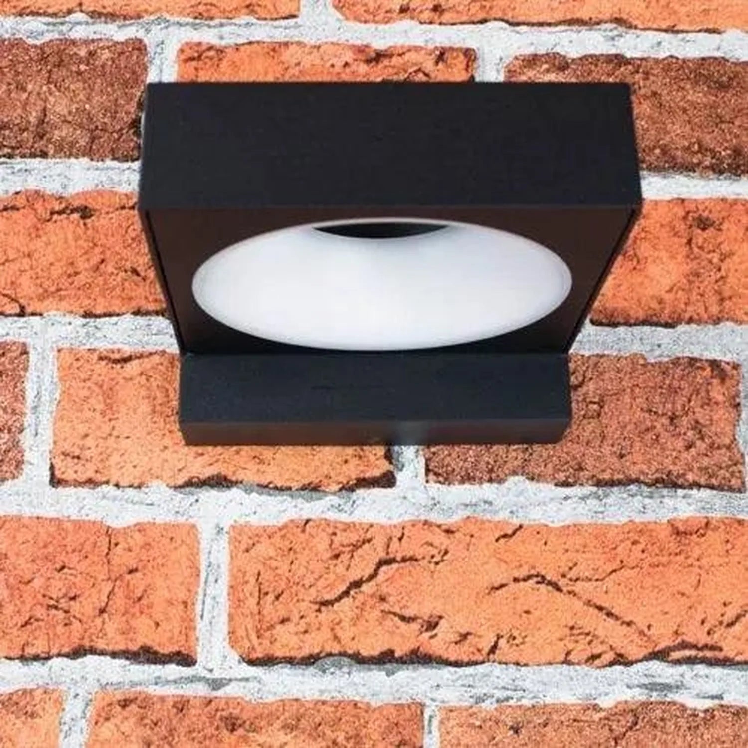 Black rectangular LED wall lamp mounted on red brick wall, white diffuser visible.