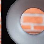 Etna LED wall lamp with gray circular housing and frosted diffuser, mounted on brick wall background.
