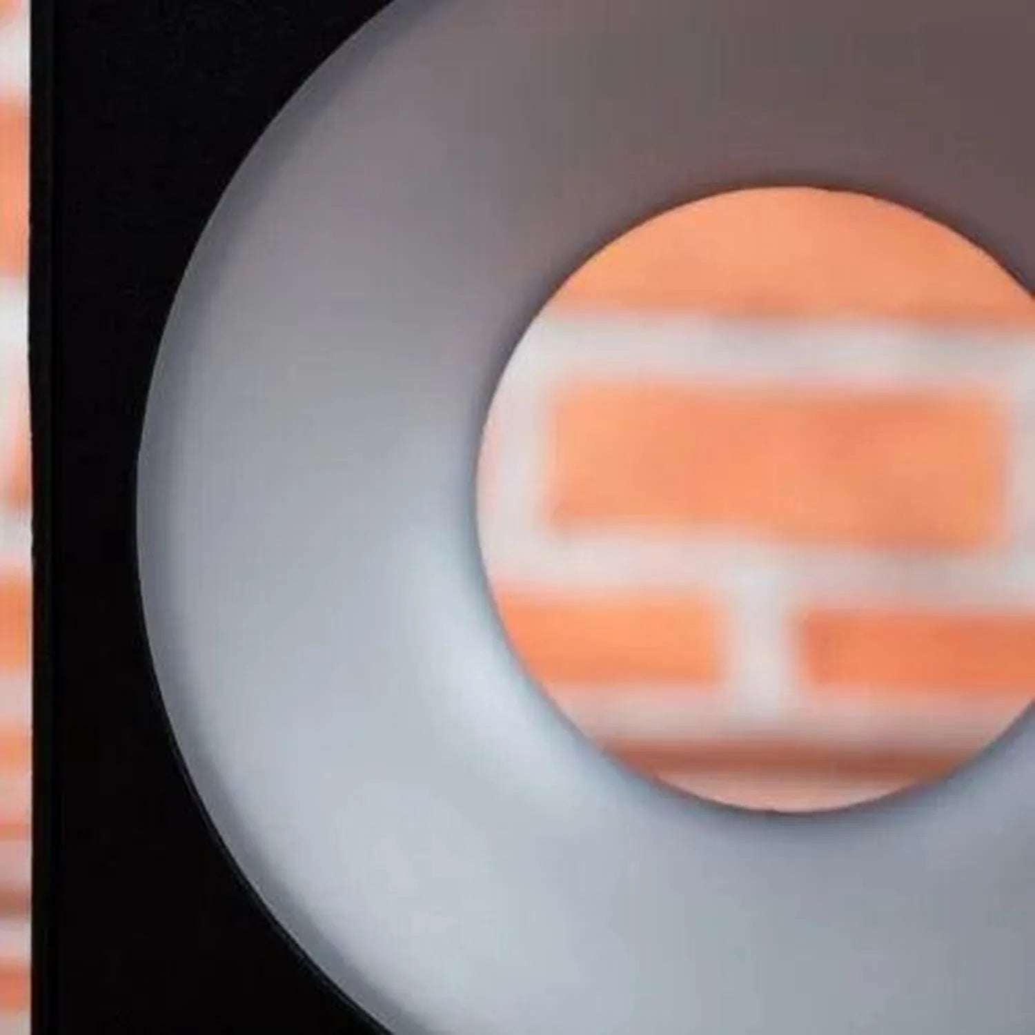 Etna LED wall lamp with gray circular housing and frosted diffuser, mounted on brick wall background.
