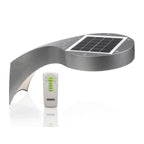 Solar wall light with curved gray metal body, integrated solar panel on top, white LED housing below, and remote control with