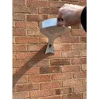 Hand holding white solar wall light with heart-shaped design against brick wall, installation shot.