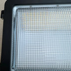 Close-up of LED wall pack fixture showing illuminated grid of LED elements with warm and cool white diodes, mounted in black 