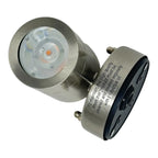 Brushed stainless steel LED spot light with recessed round faceplate and orange-tinted LED visible, shown at angle against wh