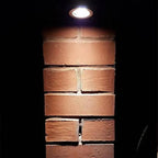 Recessed LED downlight installed in brick wall, illuminating mortar joints at night.