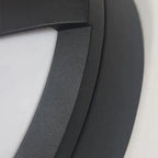 Close-up of dark gray outdoor wall light fixture showing angled eyelid design with white interior and textured surface detail
