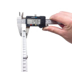 Digital caliper measuring a round white LED ceiling panel light, displaying 12.99 millimeters thickness.