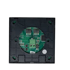 Interior view of black square smart dimmer switch showing green circuit board with DIP switches and connectors.
