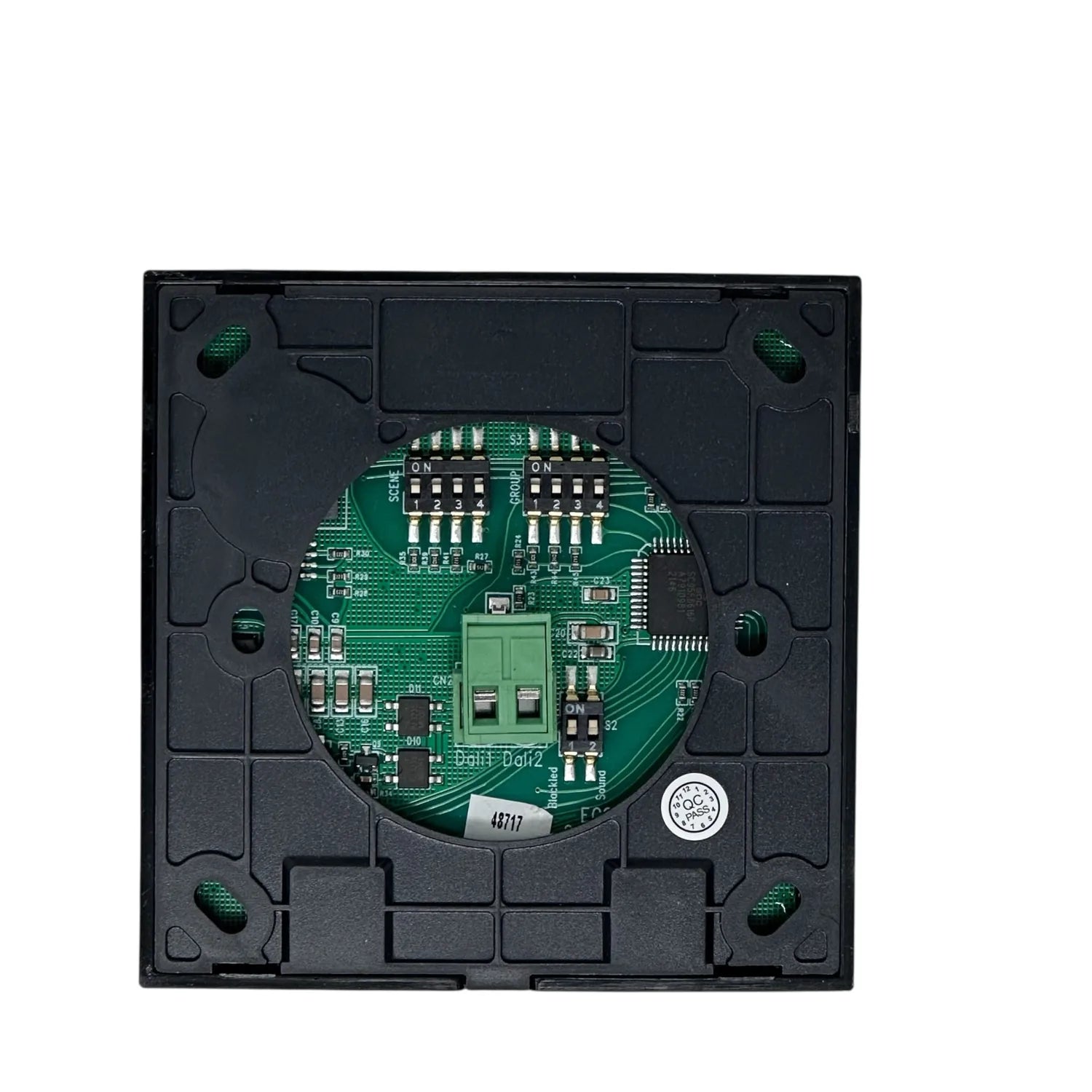 Interior view of black square smart dimmer switch showing green circuit board with DIP switches and connectors.