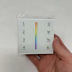 Hand holding white square LED controller with four zone buttons, power switch, mode button, brightness/speed slider, and colo