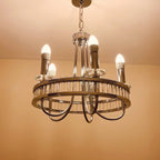 Modern brass chandelier with five lit LED candle bulbs and crystal accents, hanging from chain against beige ceiling.