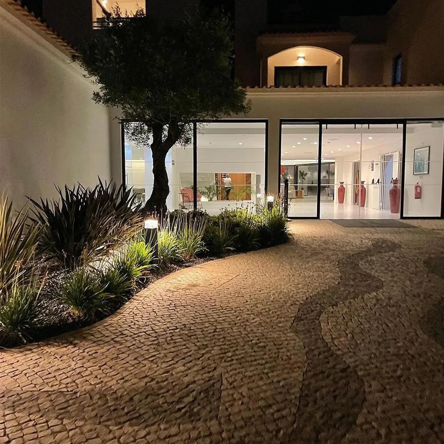 LED bollard lights illuminating a modern courtyard pathway at night, with landscaping and contemporary architecture visible.