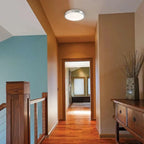 Artika Saturn flush mount LED ceiling light installed in hallway corridor with warm lighting illuminating wooden flooring and