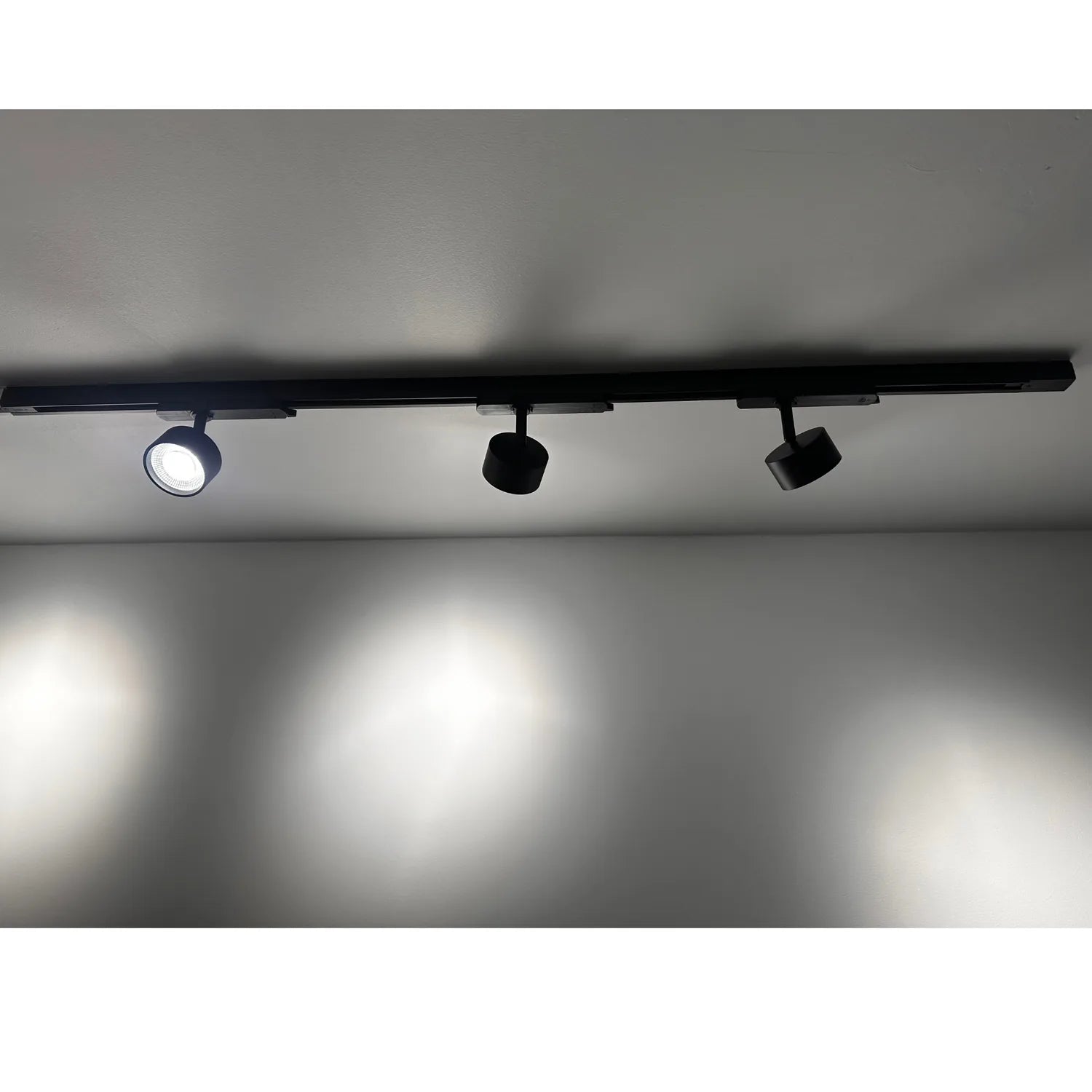 Three black LED spotlights mounted on a 1-meter track rail against a white ceiling, with the leftmost light illuminated.