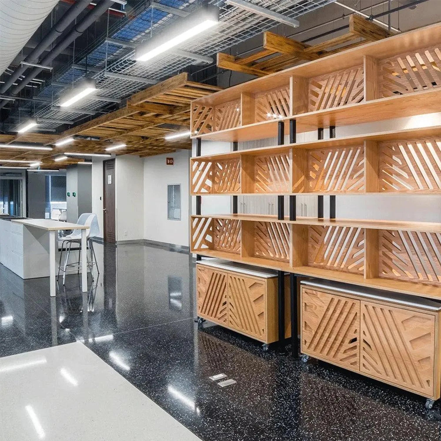Modern office interior with wooden shelving unit and LED ceiling lights illuminating polished dark flooring and white recepti