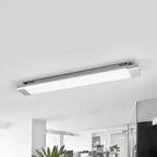 Sleek grey aluminium LED batten light mounted horizontally on white ceiling in modern office space with plants and glass part