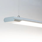 Voltaled Uranus LED batten light suspended against white background, showing elongated grey fixture with bright white light s