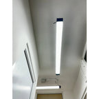 LED batten light installed on ceiling in white hallway, showing elongated rectangular fixture with dark blue end caps and bri