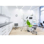 Modern dental office interior with bright LED ceiling lights, green patient chair, white cabinetry, and wood flooring.