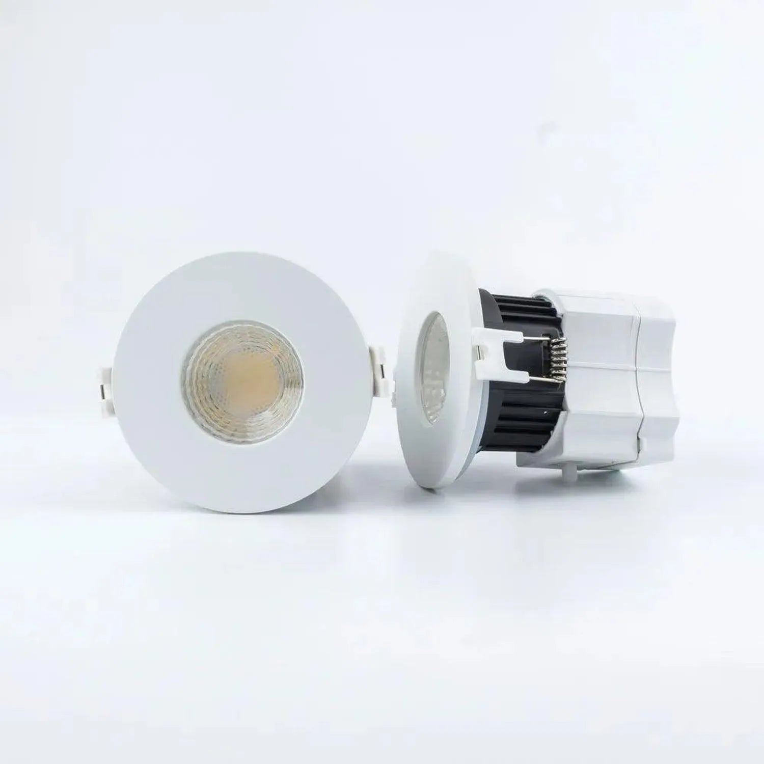 Disassembled white LED downlight showing front trim ring, middle diffuser lens, and rear housing with black heatsink fins and