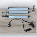 Three LED light strips with aluminum frames, a PIR motion sensor remote, and power adapter arranged on a wooden surface.
