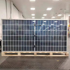 Large solar panel display mounted on wooden pallet in bright indoor showroom with fluorescent ceiling lights.