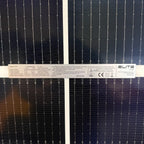 Close-up of two bifacial solar panels showing specification label with rated power, voltage, current, and safety certificatio