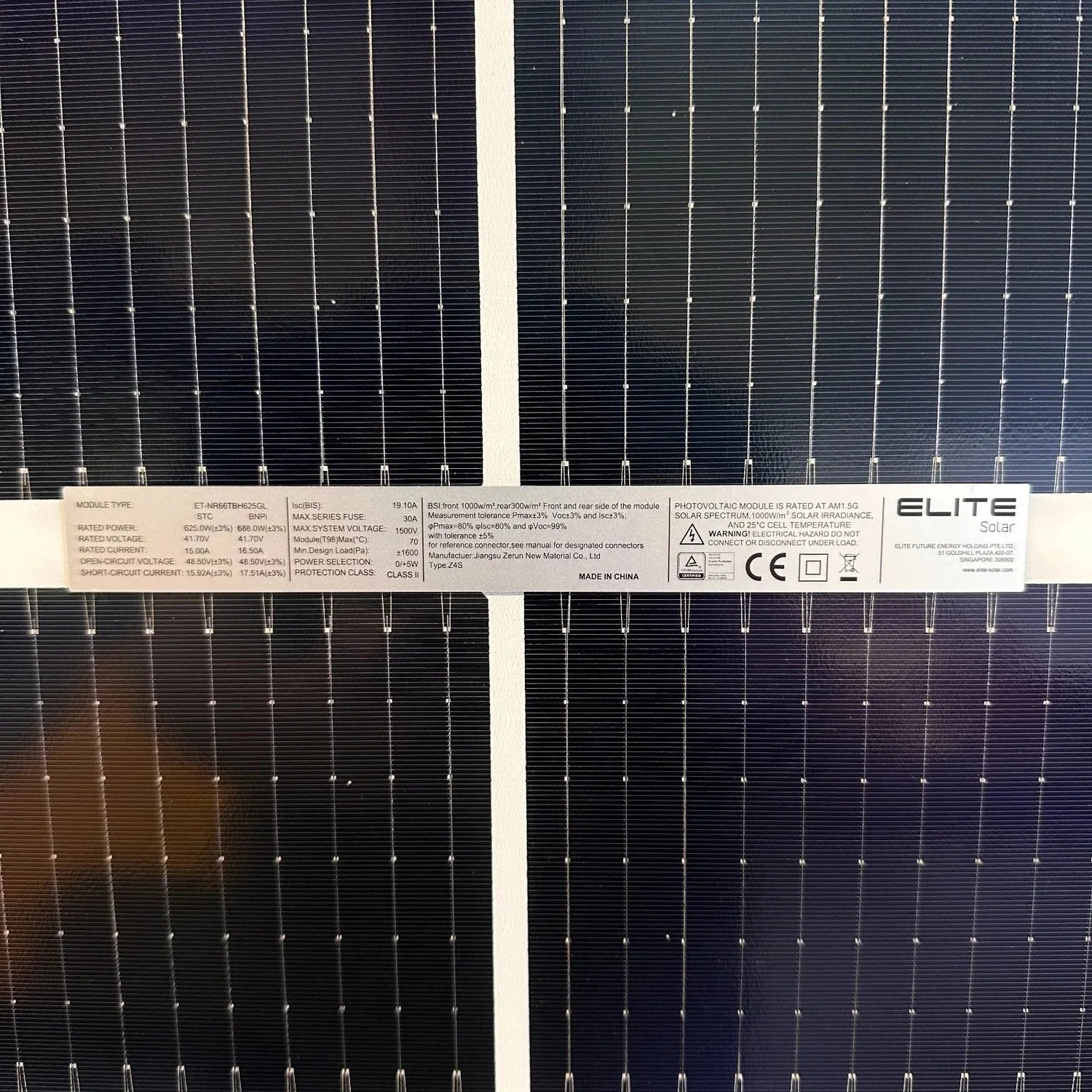 Close-up of two bifacial solar panels showing specification label with rated power, voltage, current, and safety certificatio