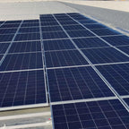 Rooftop installation of multiple solar panels arranged in rows on a flat commercial building surface.