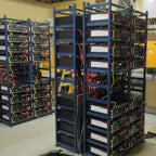 Industrial installation shot showing multiple blue-framed battery cabinets with black power units stacked vertically, display
