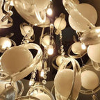 Close-up of decorative crystal chandelier with warm white G4 LED bulbs and hanging crystal prisms against dark background.