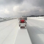 Solar panel mounting rail system installed on flat roof with red sedan car for scale reference.