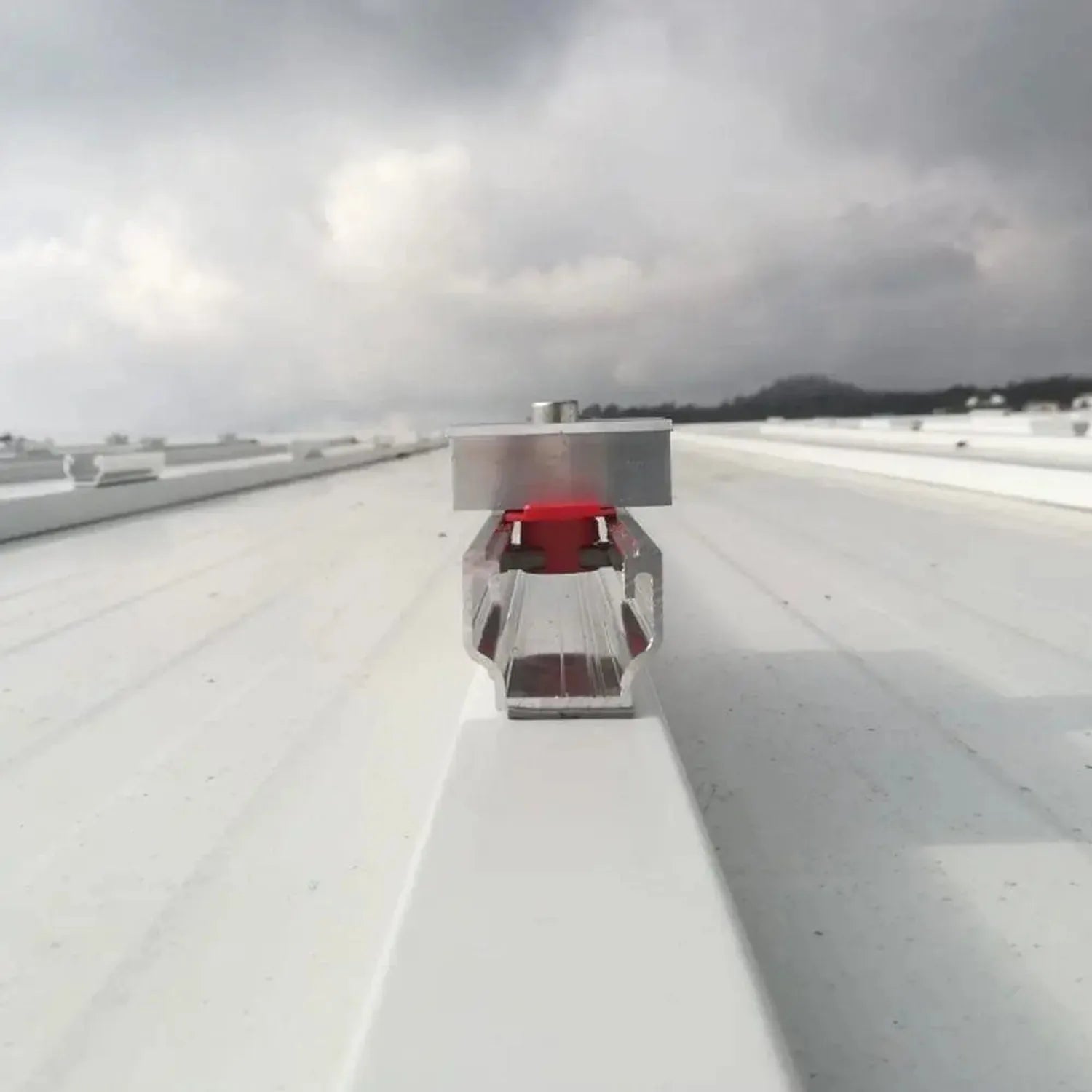 Solar panel mounting rail system installed on flat roof with red sedan car for scale reference.