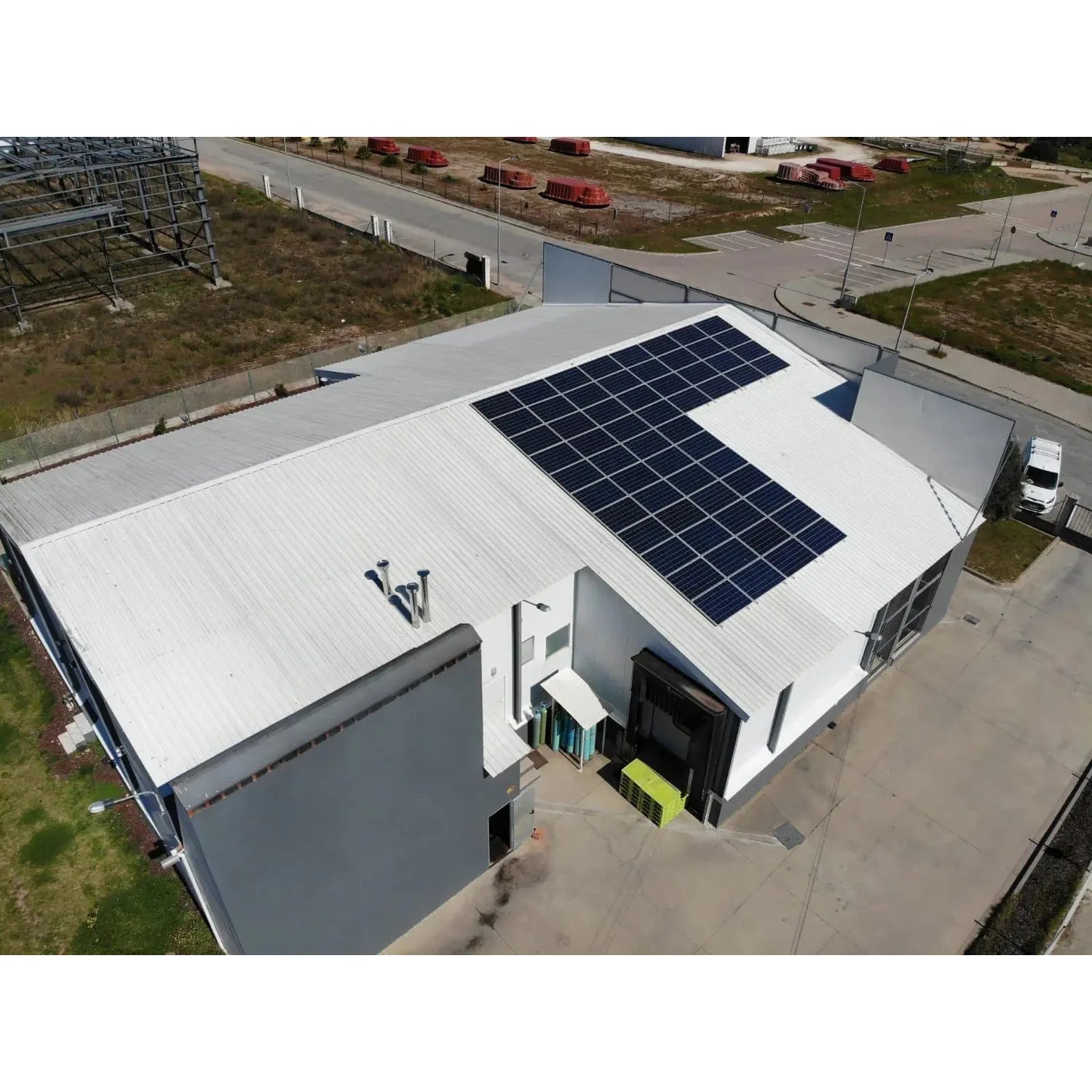 Aerial view of industrial building with solar panels mounted on white metal roof using coplanar mounting system.