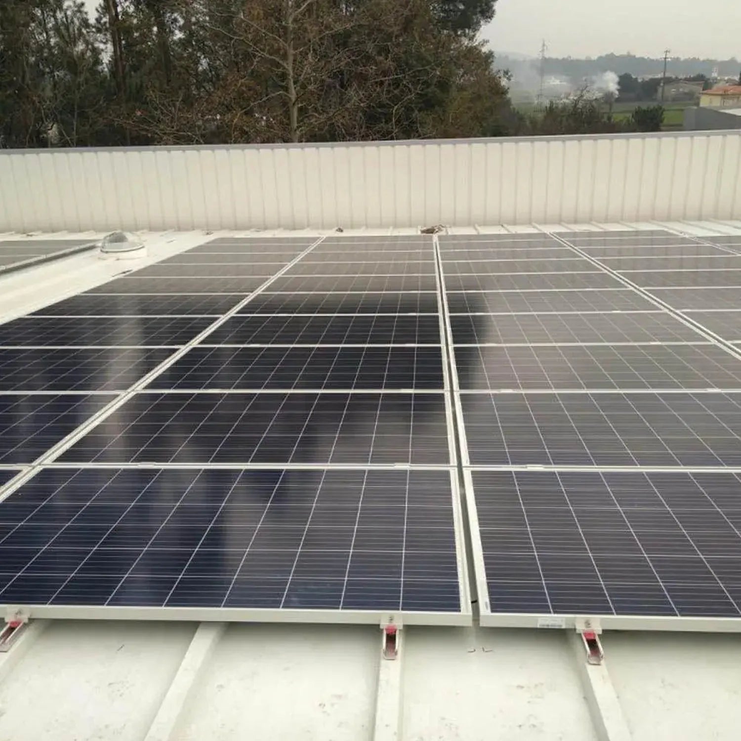 Rooftop solar panel installation showing multiple mounted photovoltaic panels secured with white aluminum rails and red clamp