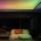 Modern bedroom with smart RGB LED strip lighting installed along ceiling, creating gradient colors from pink to green above b