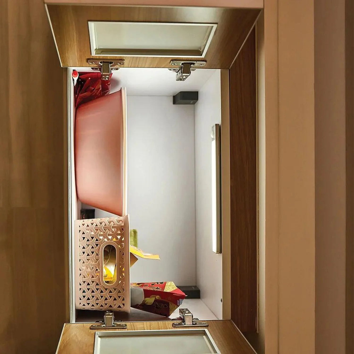 Interior view of open cabinet displaying LED under-cabinet light with geometric wooden diffuser and yellow LED glow among dec