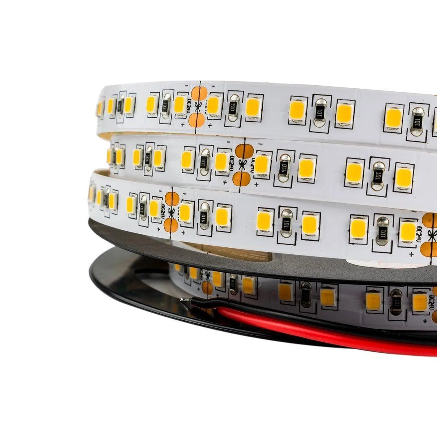 Coiled flexible LED strip light with warm white LEDs and orange solder pads, mounted on black backing with red power wire vis