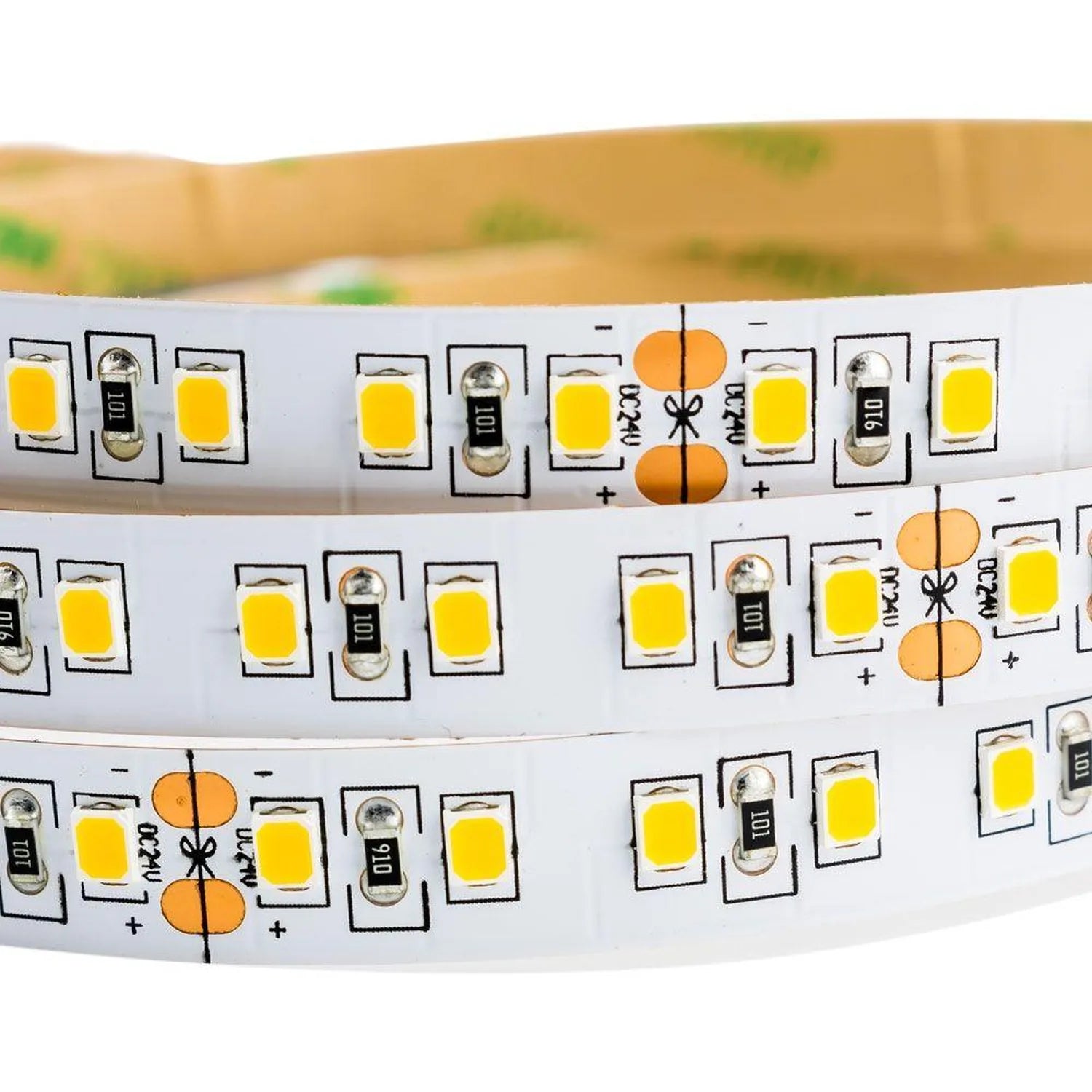 Coiled LED strip light showing yellow SMD diodes, resistors, and cut marks on white flexible PCB backing.
