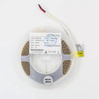 Coiled warm white LED flex strip on plastic reel with product label and loose power connector cord.