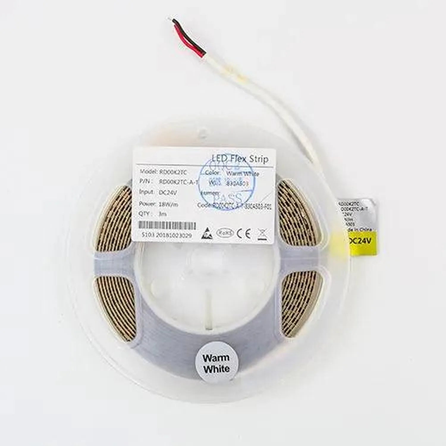 Coiled warm white LED flex strip on plastic reel with product label and loose power connector cord.