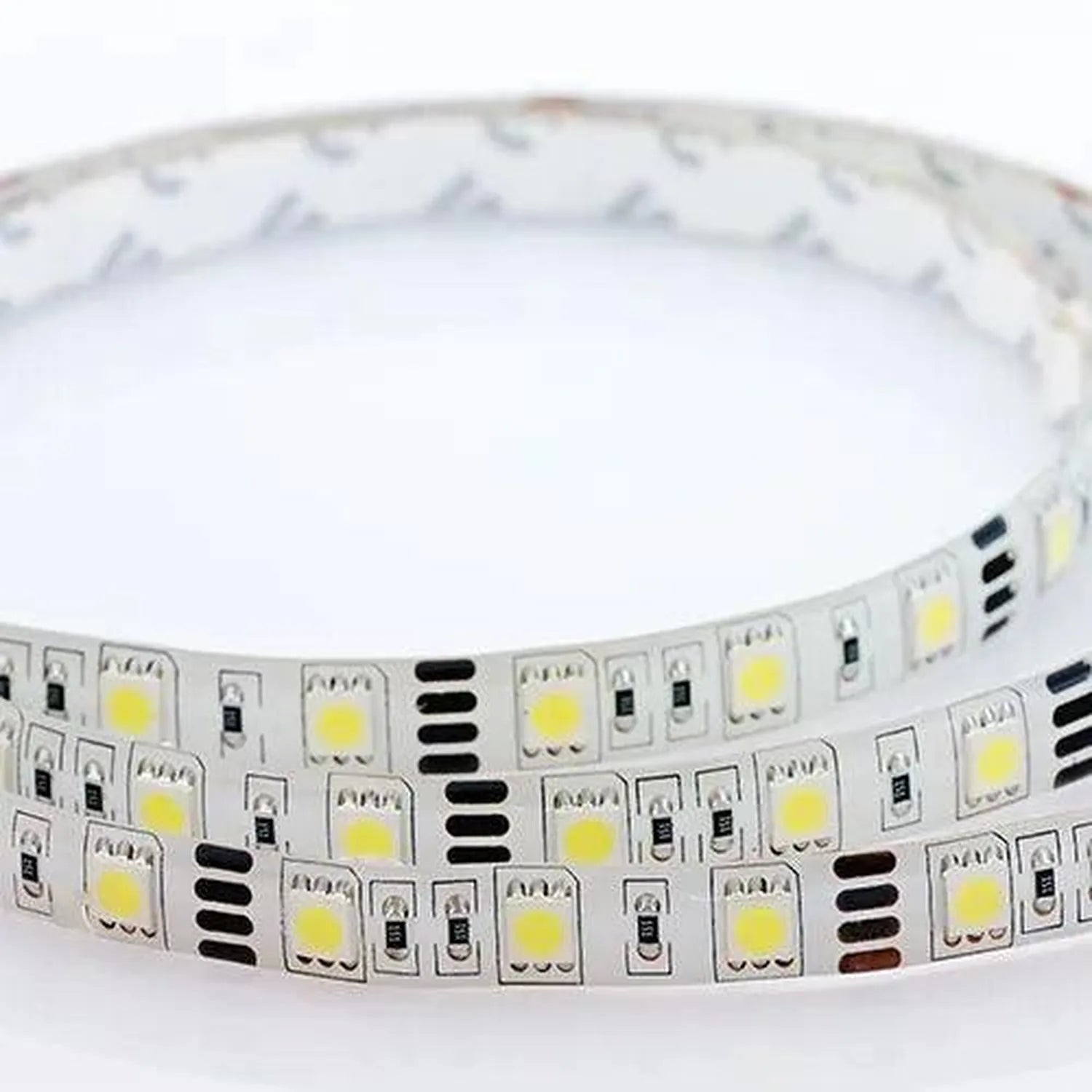 Coiled LED strip light with yellow diodes and black control components on white backing, product alone against white backgrou