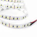 Coiled LED strip light with yellow and white SMD LEDs alternating with black control modules and copper solder pads, with red