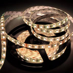 Coiled LED strip light with warm white LEDs and copper circuitry visible on black reel, product shot on dark background.