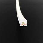 White flexible LED neon strip light shown end-on against black background, revealing internal circuitry and copper contacts.