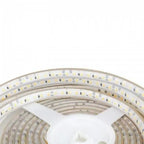Coiled LED strip light with warm white diodes on flexible white backing, showing multiple loops of the 5-meter strip.