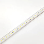 LED strip light with warm white SMD LEDs mounted on white PCB, shown at an angle against white background.
