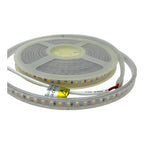 Coiled LED strip light with warm white SMD LEDs on flexible silicone tubing, showing yellow safety label and power connector.