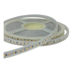 Coiled LED strip light with warm white LEDs on flexible white backing, showing individual diodes and connection points agains