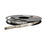 Coiled flexible LED strip light with small square LED modules and control connectors visible on white backing tape, mounted o