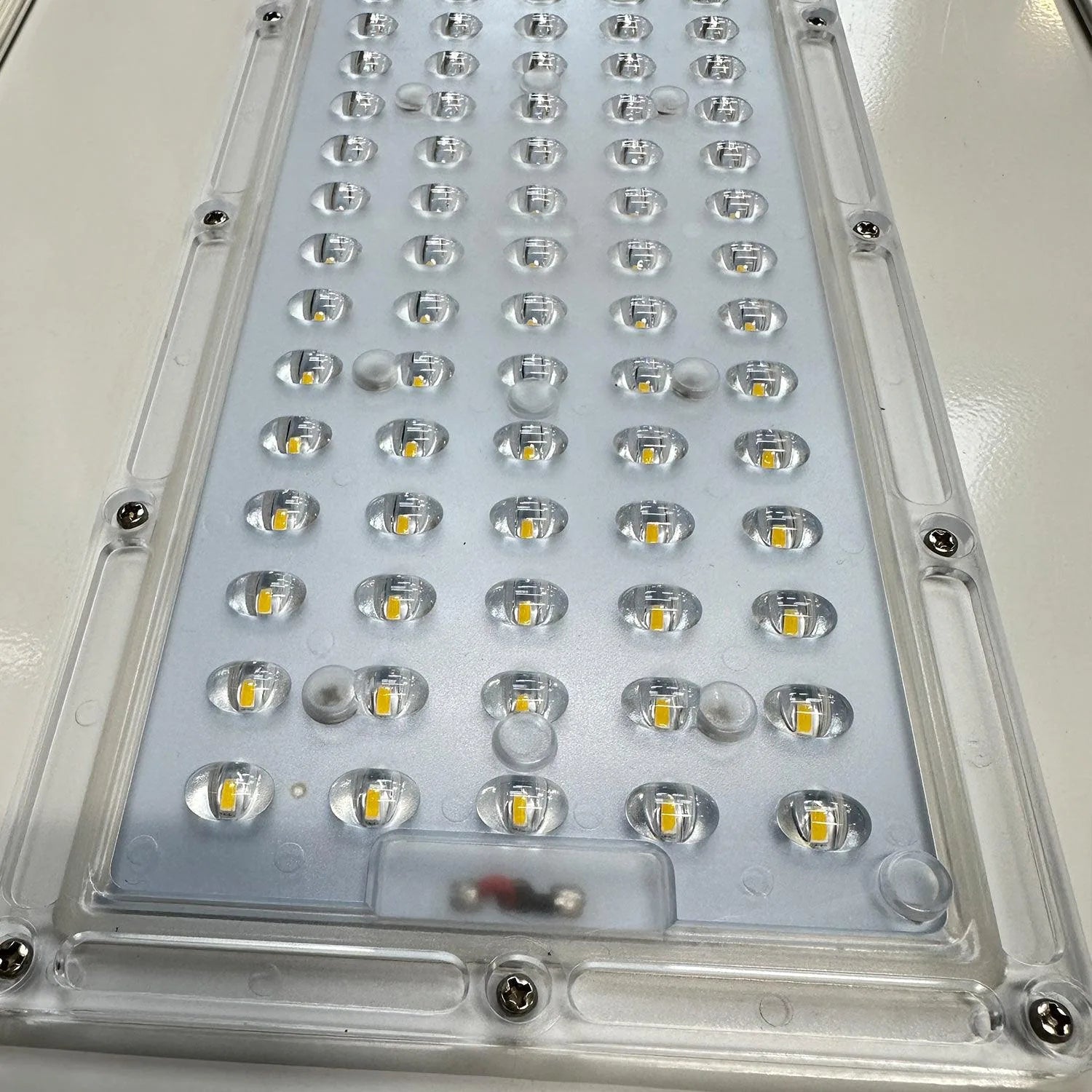 Close-up of LED panel showing 50 individual yellow and white LEDs mounted on circuit board with protective dome lenses inside